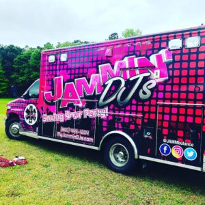 A vibrant pink and black van with text and logos advertising 