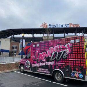 A colorful jammin' trivia company van parked outside SunTrust Park stadium under a cloudy sky.